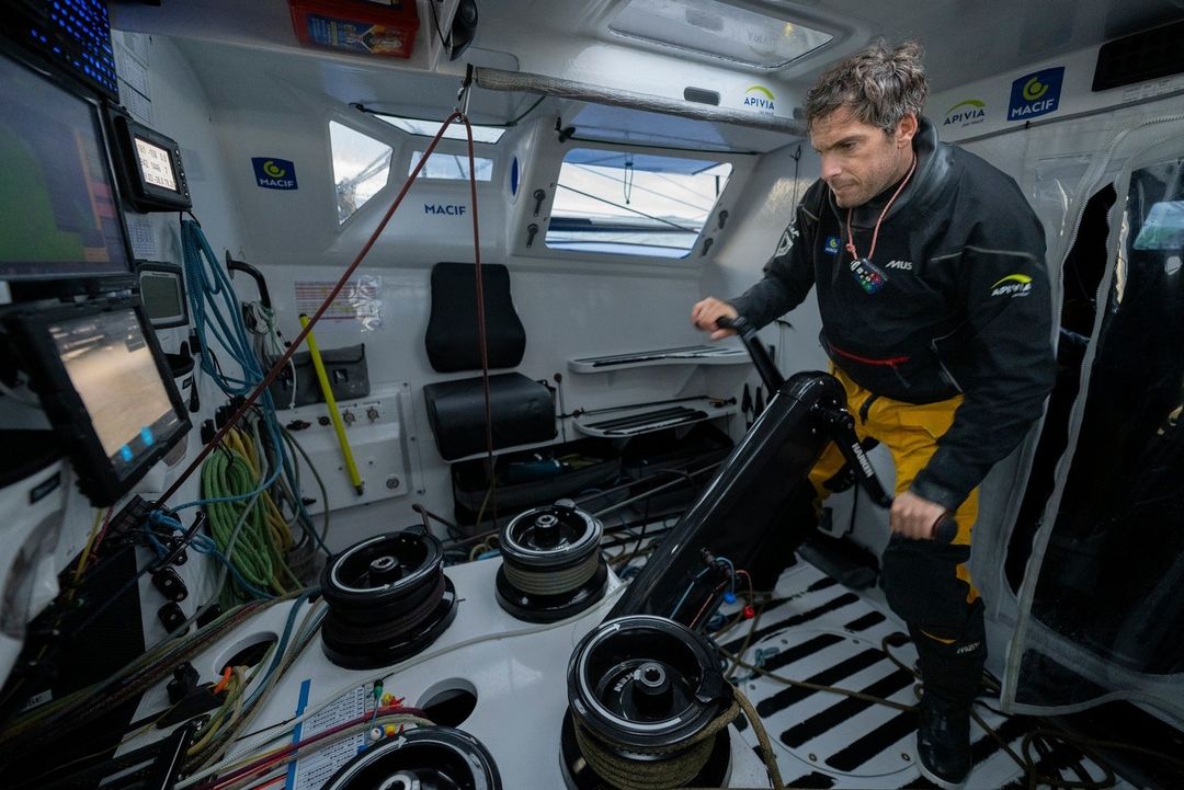 A man standing in the boat's cockpit, firmly gripping the motor for control.