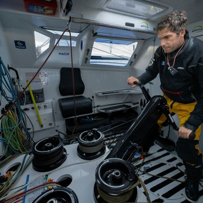 A man standing in the boat's cockpit, firmly gripping the motor for control.